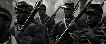 Movie still from “Emancipation” (2022), directed by Antoine Fuqua – A group of men in uniforms are holding guns; Medium shot, Low angle
