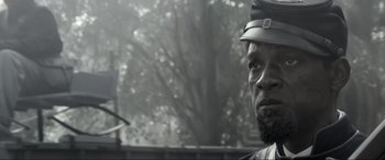 Movie still from “Emancipation” (2022), directed by Antoine Fuqua – A man with a beard wearing a hat and looking at the camera; Close Up shot, Low angle