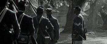 Movie still from “Emancipation” (2022), directed by Antoine Fuqua – A black and white photo of a group of men standing next to each other; Wide shot, Over the shoulder angle