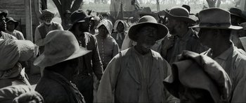 Movie still from “Emancipation” (2022), directed by Antoine Fuqua – A group of people standing in a field with hats on; Medium shot, Over the shoulder angle