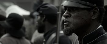 Movie still from “Emancipation” (2022), directed by Antoine Fuqua – A black and white photo of a man with a beard; Close Up shot, Over the shoulder angle
