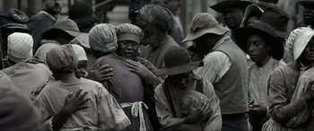 Movie still from “Emancipation” (2022), directed by Antoine Fuqua – A group of people that are gathered around a woman; Medium shot, Over the shoulder angle