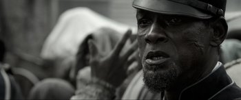 Movie still from “Emancipation” (2022), directed by Antoine Fuqua – A black and white photo of a man with a hat on; Close Up shot, Low angle