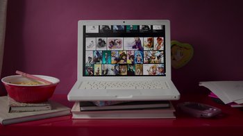 Movie still from “Embrace the Panda: Making Turning Red” (2022), directed by Erica Milsom – An open laptop computer sitting on top of a stack of books; Wide shot, High angle
