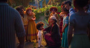 Movie still from “Encanto” (2021), directed by Charise Castro Smith – A group of people gathered around a young child; Wide shot, Over the shoulder angle