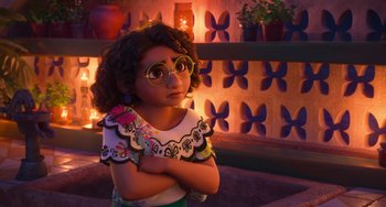 Movie still from “Encanto” (2021), directed by Charise Castro Smith – A young girl wearing glasses with her arms crossed; Medium shot, Over the shoulder angle
