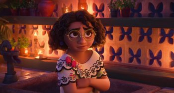 Movie still from “Encanto” (2021), directed by Charise Castro Smith – A young girl wearing glasses with her arms crossed; Close Up shot, Over the shoulder angle