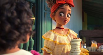 Movie still from “Encanto” (2021), directed by Charise Castro Smith – A girl with a red bow on her head is looking at a stack of pancakes; Close Up shot, Over the shoulder angle