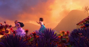 Movie still from “Encanto” (2021), directed by Charise Castro Smith – A woman is walking through a field of flowers at sunset; Extreme Wide shot, Over the shoulder angle