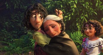 Movie still from “Encanto” (2021), directed by Charise Castro Smith – An old woman holding a young man in her arms; Medium shot, Over the shoulder angle