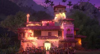Movie still from “Encanto” (2021), directed by Charise Castro Smith – A group of people standing around a building with fire coming out of it; Extreme Wide shot, Low angle