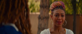 Movie still from “End of the Road” (2022), directed by Millicent Shelton – A person wearing a colorful head wrap; Close Up shot, Over the shoulder angle