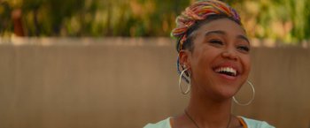 Movie still from “End of the Road” (2022), directed by Millicent Shelton – A person with a colorful head dress; Close Up shot, Over the shoulder angle