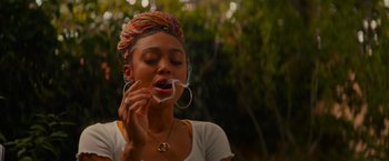 Movie still from “End of the Road” (2022), directed by Millicent Shelton – A young woman is blowing bubbles in her mouth; Close Up shot, Over the shoulder angle