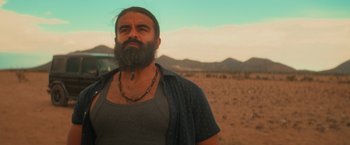 Movie still from “End of the Road” (2022), directed by Millicent Shelton – A man with a long beard standing in the desert; Close Up shot, Low angle