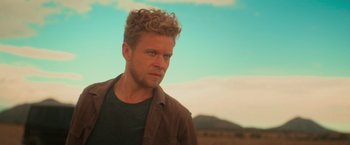 Movie still from “End of the Road” (2022), directed by Millicent Shelton – A person wearing a brown shirt; Close Up shot, Low angle