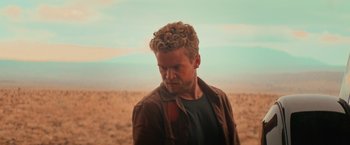 Movie still from “End of the Road” (2022), directed by Millicent Shelton – A person wearing a brown jacket; Close Up shot, Low angle