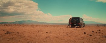 Movie still from “End of the Road” (2022), directed by Millicent Shelton – A man standing next to a truck in the desert; Extreme Wide shot, High angle