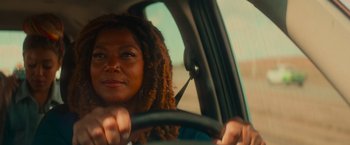 Movie still from “End of the Road” (2022), directed by Millicent Shelton – A woman with dreads is driving a car; Close Up shot, Over the shoulder angle