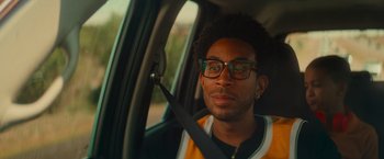 Movie still from “End of the Road” (2022), directed by Millicent Shelton – A man sitting in the passenger seat of a car; Close Up shot, Over the shoulder angle