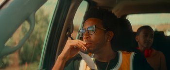 Movie still from “End of the Road” (2022), directed by Millicent Shelton – A man sitting in the passenger seat of a car; Close Up shot, Low angle