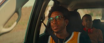 Movie still from “End of the Road” (2022), directed by Millicent Shelton – A man sitting in the passenger seat of a car; Close Up shot, Over the shoulder angle