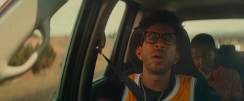 Movie still from “End of the Road” (2022), directed by Millicent Shelton – A man sitting in the passenger seat of a car; Close Up shot, Low angle