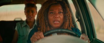 Movie still from “End of the Road” (2022), directed by Millicent Shelton – A woman with dreads is driving a car; Close Up shot, Over the shoulder angle