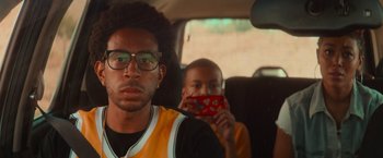 Movie still from “End of the Road” (2022), directed by Millicent Shelton – Two young men in the back seat of a car; Close Up shot, Over the shoulder angle