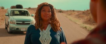 Movie still from “End of the Road” (2022), directed by Millicent Shelton – A person with dreadlocks on a dirt road; Close Up shot, Over the shoulder angle