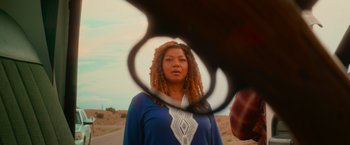 Movie still from “End of the Road” (2022), directed by Millicent Shelton – A woman standing on a dirt road looking into a mirror; Close Up shot, Over the shoulder angle
