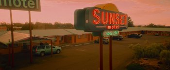 Movie still from “End of the Road” (2022), directed by Millicent Shelton – A motel sign is lit up at sunset; Extreme Wide shot, High angle