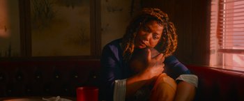 Movie still from “End of the Road” (2022), directed by Millicent Shelton – A woman sitting at a table holding a child; Close Up shot, Over the shoulder angle