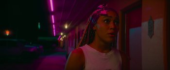 Movie still from “End of the Road” (2022), directed by Millicent Shelton – A woman with braids standing in a dark room; Close Up shot, Low angle