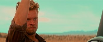 Movie still from “End of the Road” (2022), directed by Millicent Shelton – A person with a beard and curly hair; Close Up shot, Over the shoulder angle