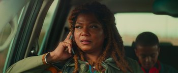 Movie still from “End of the Road” (2022), directed by Millicent Shelton – A woman with dreads talking on a cell phone; Close Up shot, Over the shoulder angle