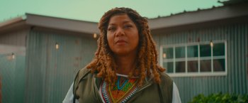 Movie still from “End of the Road” (2022), directed by Millicent Shelton – A woman with dreads standing in front of a building; Close Up shot, Low angle