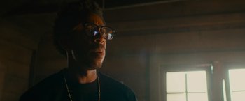 Movie still from “End of the Road” (2022), directed by Millicent Shelton – A man wearing glasses and a black shirt; Close Up shot, Low angle