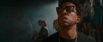 Movie still from “End of the Road” (2022), directed by Millicent Shelton – A person wearing glasses; Close Up shot, Low angle