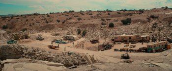 Movie still from “End of the Road” (2022), directed by Millicent Shelton – An aerial view of an area with a lot of rubble and cars; Extreme Wide shot, High angle