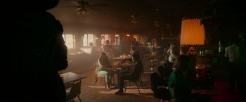 Movie still from “End of the Road” (2022), directed by Millicent Shelton – A group of people sitting at tables in a restaurant; Wide shot, High angle