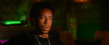 Movie still from “End of the Road” (2022), directed by Millicent Shelton – A person sitting in a chair wearing a necklace; Close Up shot, Over the shoulder angle