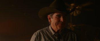 Movie still from “End of the Road” (2022), directed by Millicent Shelton – A person wearing a cowboy hat; Close Up shot, Over the shoulder angle