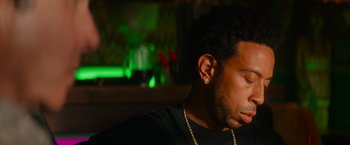 Movie still from “End of the Road” (2022), directed by Millicent Shelton – A person sitting in front of a green light; Close Up shot, Low angle