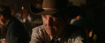 Movie still from “End of the Road” (2022), directed by Millicent Shelton – A person wearing a cowboy hat; Close Up shot, Over the shoulder angle