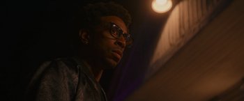 Movie still from “End of the Road” (2022), directed by Millicent Shelton – A person wearing glasses; Close Up shot, Low angle