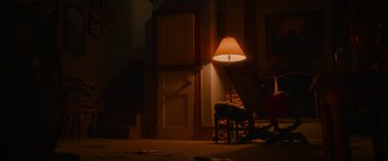 Movie still from “End of the Road” (2022), directed by Millicent Shelton – A lamp is lit up in a dimly - lit room; Extreme Wide shot, High angle