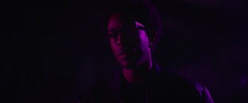 Movie still from “End of the Road” (2022), directed by Millicent Shelton – A man with glasses is in a dark room; Close Up shot, Low angle