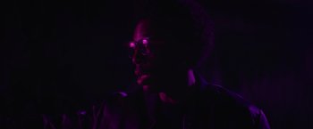 Movie still from “End of the Road” (2022), directed by Millicent Shelton – A man with glasses in the dark with purple lighting; Close Up shot, Low angle