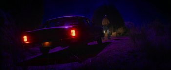 Movie still from “End of the Road” (2022), directed by Millicent Shelton – A man is standing next to a truck at night; Wide shot, Low angle